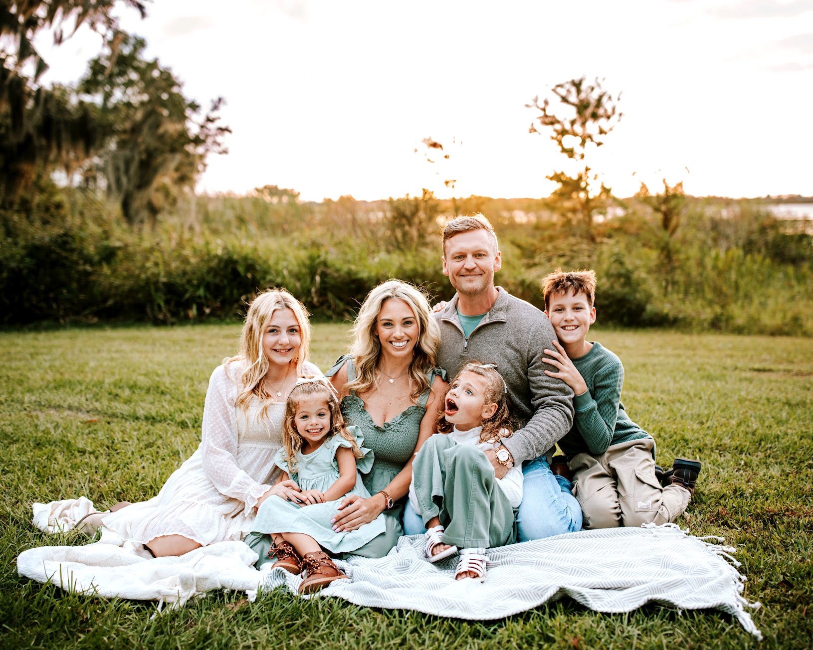 Josh, Jessica, and their children gathered together on a blanket in the grass