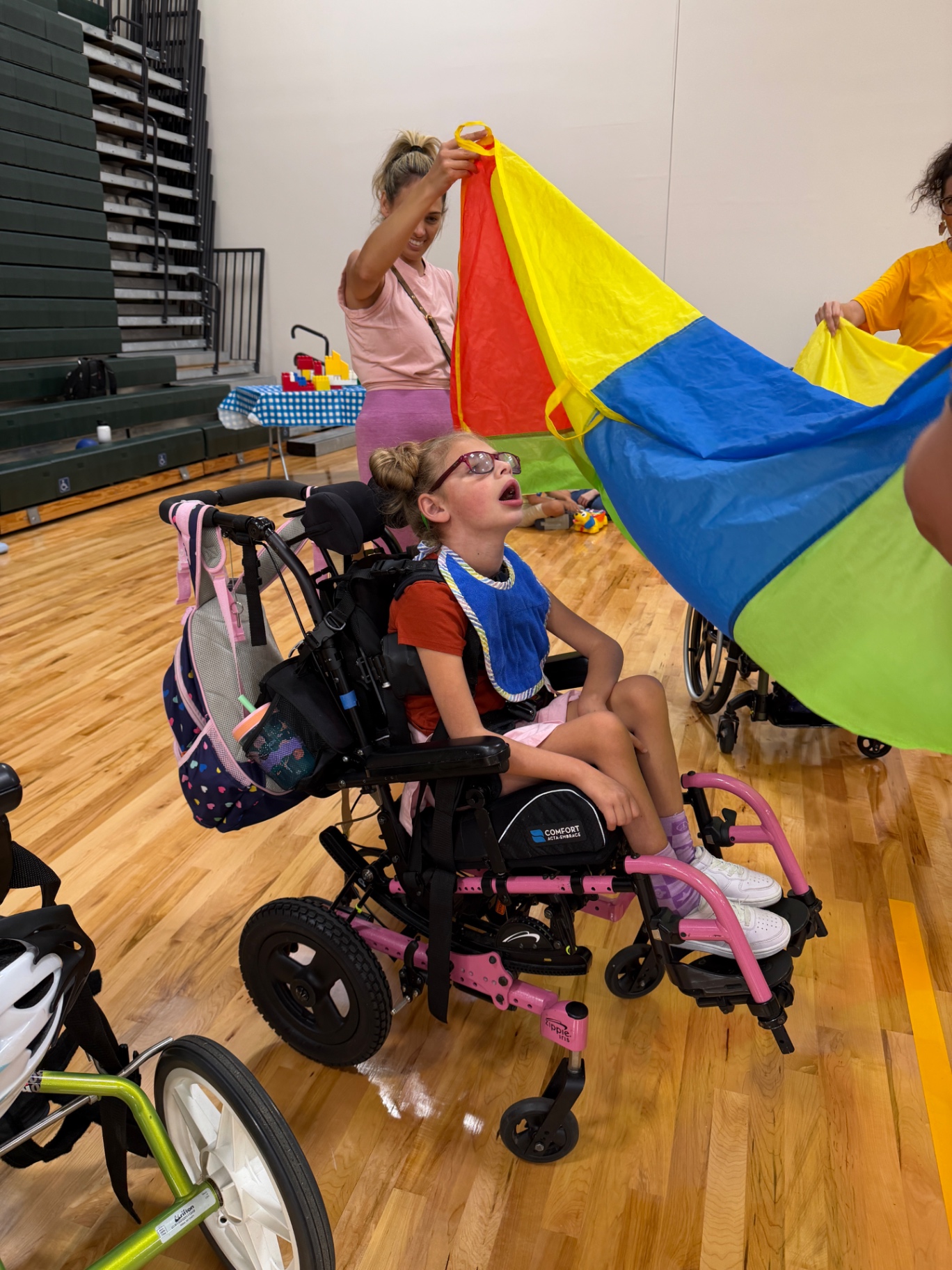 Ava in her wheelchair watching a bright play parachute