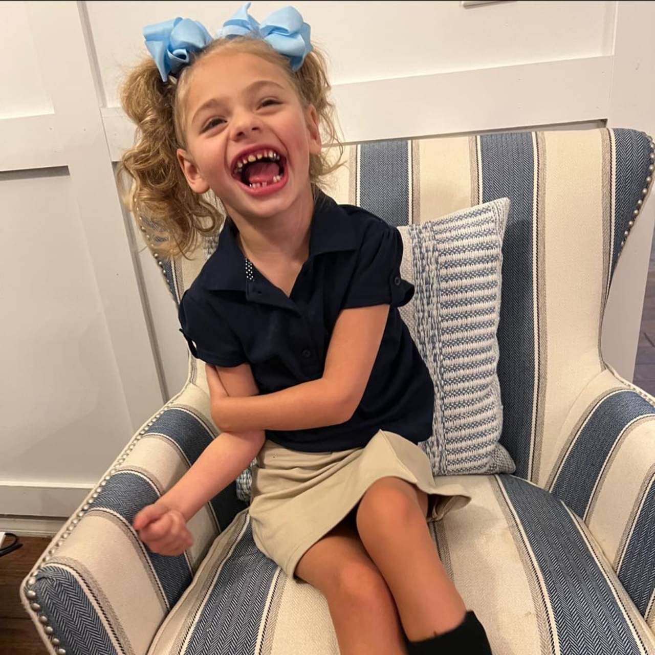 Ava dressed for a school day, laughing in an armchair