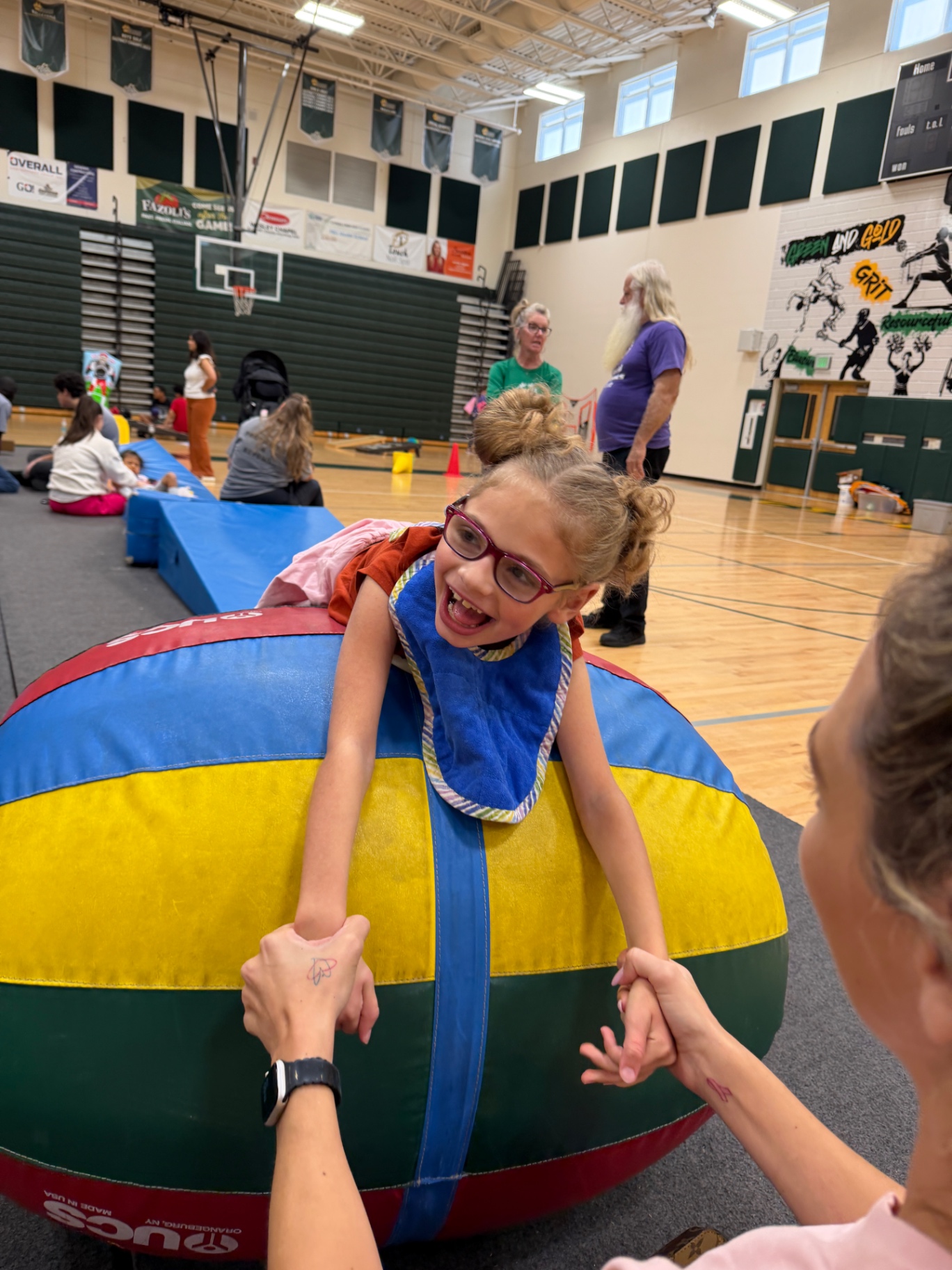 Ava beaming during physical therapy, holding hands over a large ball